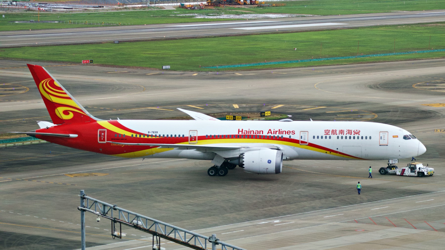 787-9 被牵引车拖行,地勤在机翼下穿行。